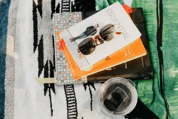 A pile of digital marketing books on a patterned blanket with a cup of coffee nearby